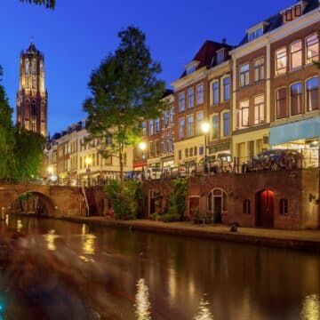 Vue du canal de Utrecht de nuit, avec les lampadaires allumés donnant une ambiance nocturne chaleureuse.